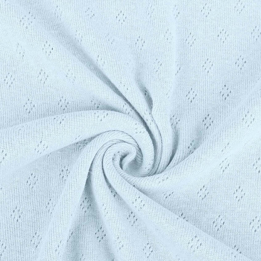 Baby blue pointelle knit jersey fabric from Once Upon A Fabric with diamond-shaped perforations. The pointelle cotton jersey fabric appears lightweight, suggesting it may be perfect for baby clothes or accessories.