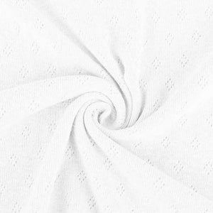 White pointelle knit jersey fabric from Once Upon A Fabric with diamond-shaped perforations. The pointelle cotton jersey fabric appears lightweight, suggesting it may be perfect for baby clothes or accessories.