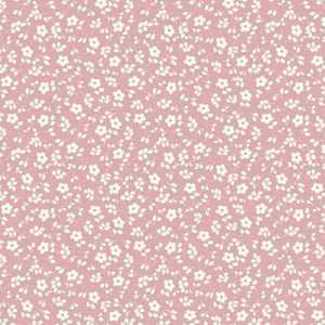 A pink background with a repeating pattern of small white flowers and green leaves. The flowers are evenly distributed, creating a uniform and symmetrical design, perfect for dressmaking fabric. This Cotton Jersey Fabric - Millefleur Old Rose by Once Upon A Fabric is also Oeko-Tex 100 certified.