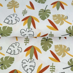 A piece of white muslin fabric with a pattern of tropical leaves and plants in shades of green, yellow, orange, and brown. Some leaves are large and have multiple segments, while others are smaller and more simplistic. The slightly folded REMNANT 98 CM Double Gauze - Autumn Leaves by Once Upon A Fabric is perfect for creating baby items.