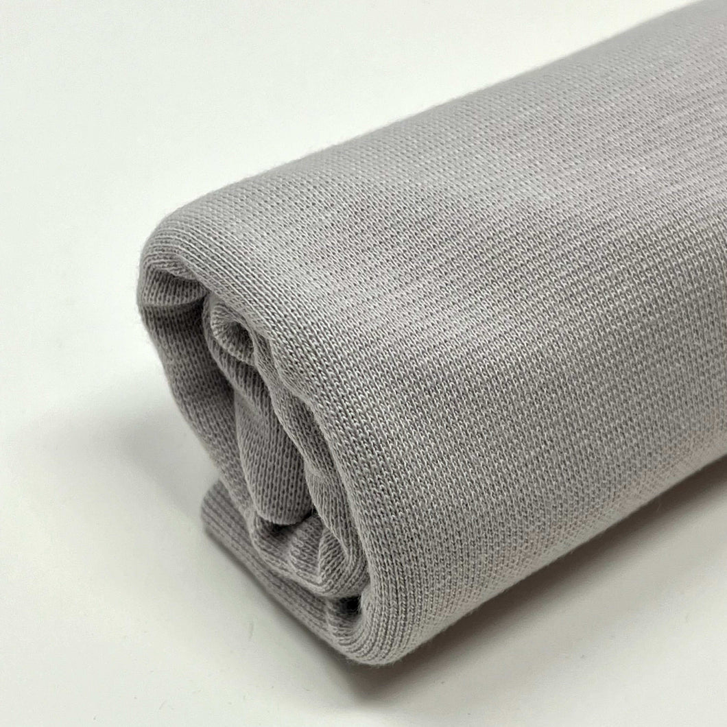 A single rolled-up light gray fabric is displayed against a white background. The material appears to be Organic Tubular Cuff ribbing - SILVER GREY by MiskaHryzka, perfect for creating stretchy waistband material with its knit texture.