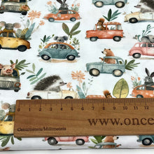 Load image into Gallery viewer, Organic GOTS Cotton Jersey with a whimsical pattern featuring small animals driving colourful cars. The digitally printed design includes mice, rabbits, hedgehogs, and elephants, surrounded by various plants and flowers against a white background.
