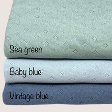 Load image into Gallery viewer, Three folded fabrics with labels are stacked vertically. From top to bottom: sea green, baby blue, and Pointelle Jersey - Vintage Blue by Once Upon A Fabric. Each lightweight fabric displays a subtle diamond pattern and is crafted from pointelle cotton jersey, perfect for creating soft baby clothes.
