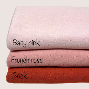 Three knitted fabric swatches, made from lightweight cotton fabric, are stacked on top of each other. They are labeled in black text as follows: the top swatch is "Baby pink," the middle swatch is "Pointelle Jersey - French Rose" by Once Upon A Fabric, and the bottom swatch is "Brick." These samples proudly boast Oeko-Tex 100 certification.