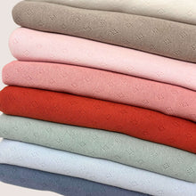 Load image into Gallery viewer, A stack of lightweight, Oeko-Tex 100 certified knitted fabric pieces, each in different colors: beige, light pink, pink, red, light green, and blue. These Once Upon A Fabric Pointelle Jersey - Baby Blue fabrics feature a subtle, small diamond pattern repeated across their surfaces.
