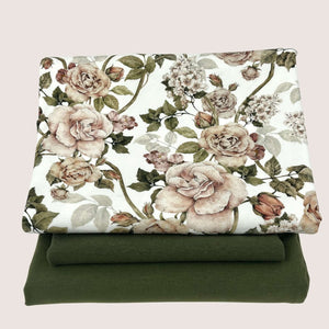 A folded piece of floral-patterned fabric with a design of pink and green flowers and leaves is placed on top of a folded green piece of cotton jersey fabric. Both fabrics, perfect for use as cuff ribbing, are neatly stacked against a plain, light-colored background. This is the Jersey Remnants Bundle 1.3 m from Once Upon A Fabric.