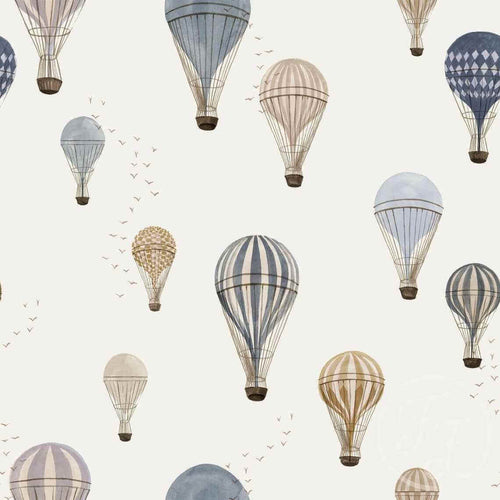 Patterned stretch cotton jersey fabric with blue hot air balloons of various designs and colors drifting in the sky on an off white background, complemented by small, scattered birds. Family Fabrics Design in the UK.