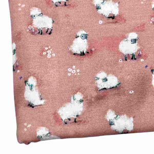 Baby fabric features a delightful pattern of small white sheep on a pink background, interspersed with tiny white flowers.