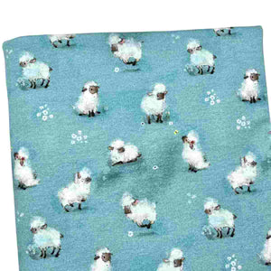 Baby fabric features a delightful pattern of small white sheep on a blue background, interspersed with tiny white flowers.