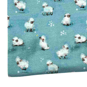 Baby fabric features a delightful pattern of small white sheep on a blue background, interspersed with tiny white flowers.